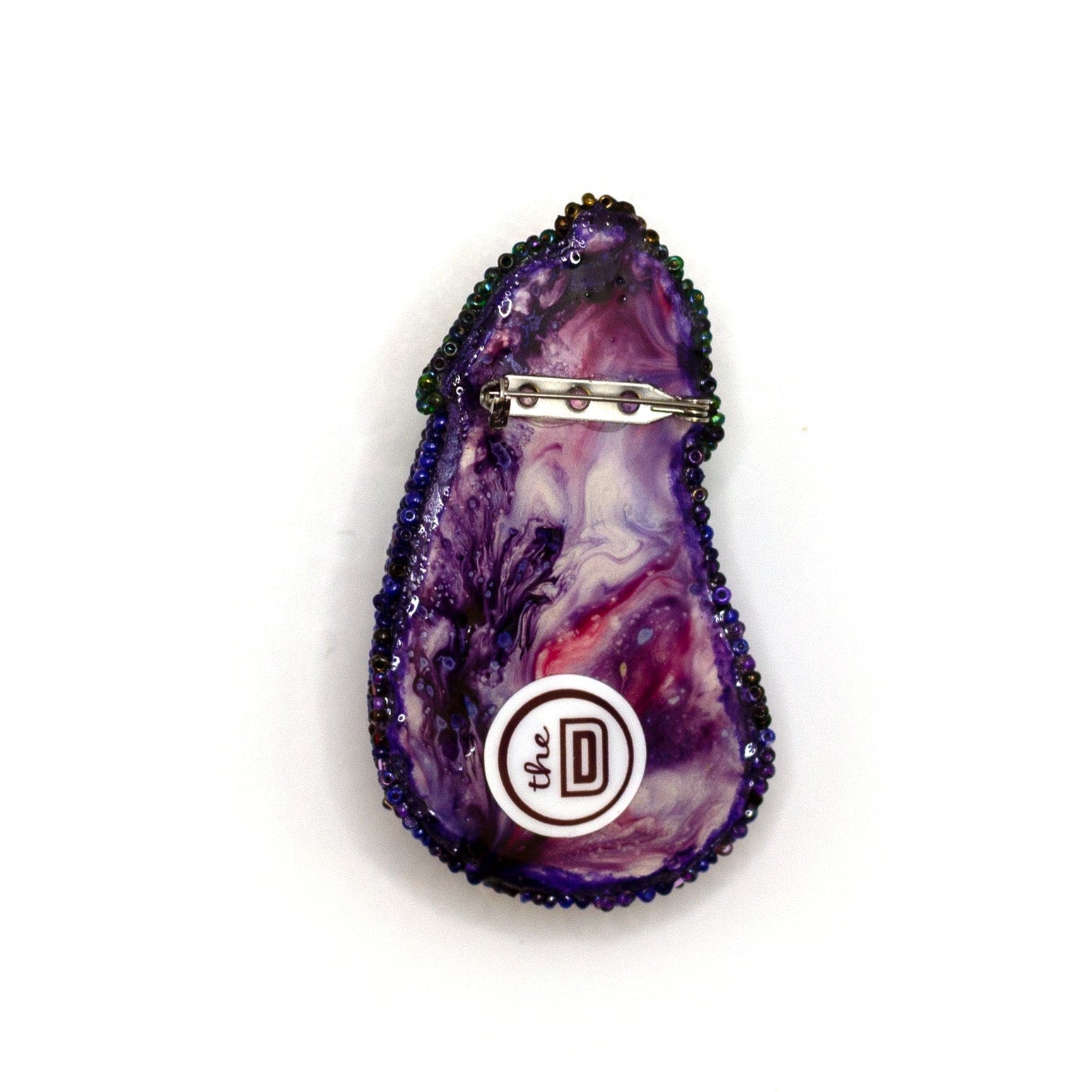 Back view of a handmade beaded eggplant brooch set on a white background showing pin fastener.