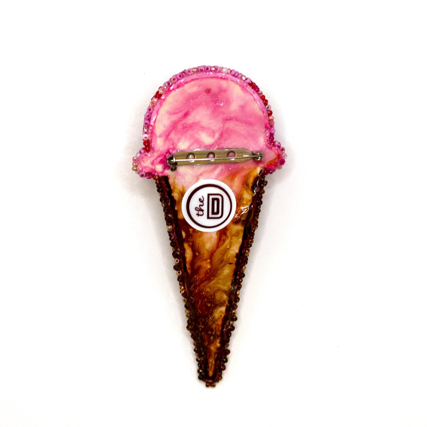 Back view of handmade beaded pink ice cream cone brooch on a white background showing pin fastener.