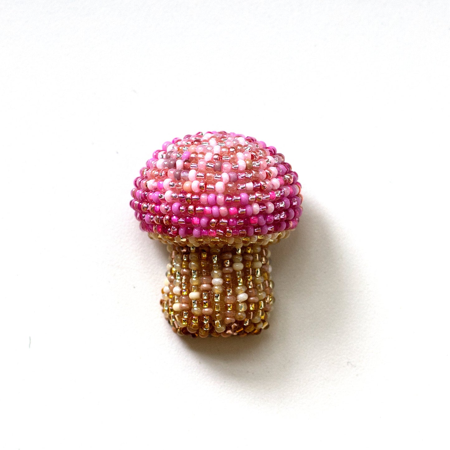 A small mushroom-shaped beaded brooch with a pink beaded cap and a gold beaded stem, shown on a plain white background.