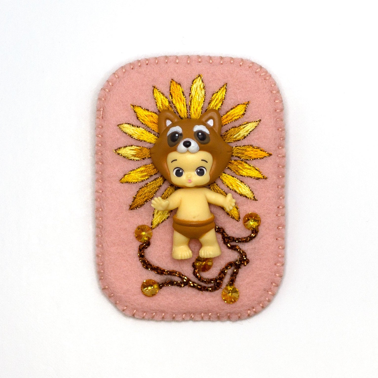 Happi Twozie brooch embroidered with a daisy on a white background.