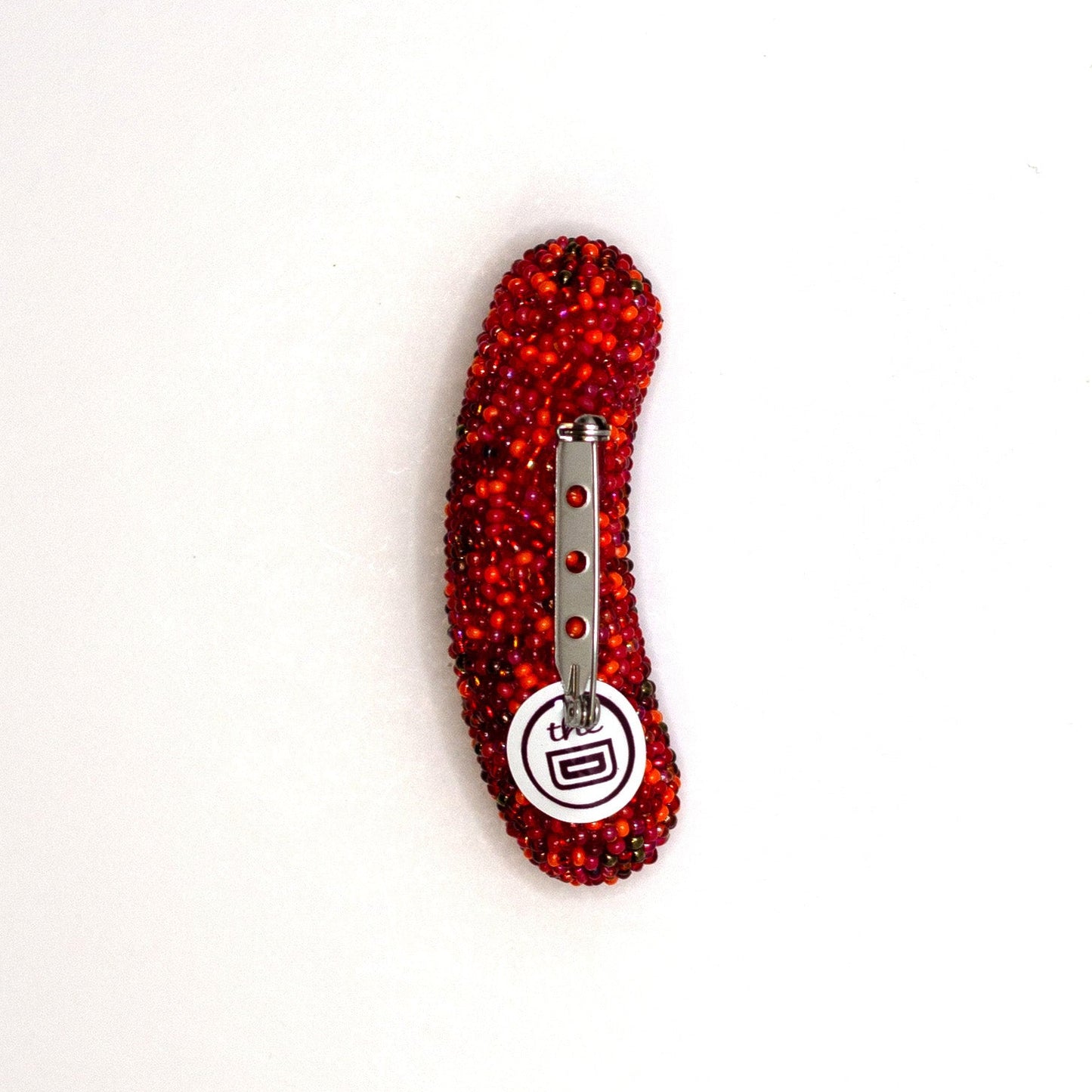 Back view of a handmade beaded hot dog brooch on a white background showing pin fastener.