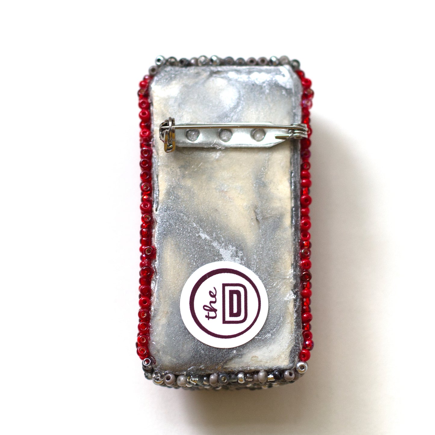 Back view of a beaded Coke pop can brooch showing the pin fastener.