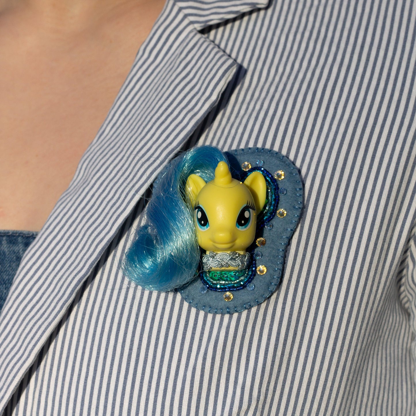 Closeup of a handmade beaded brooch featuring Lemony Gem My Little Pony worn on a striped lapel.