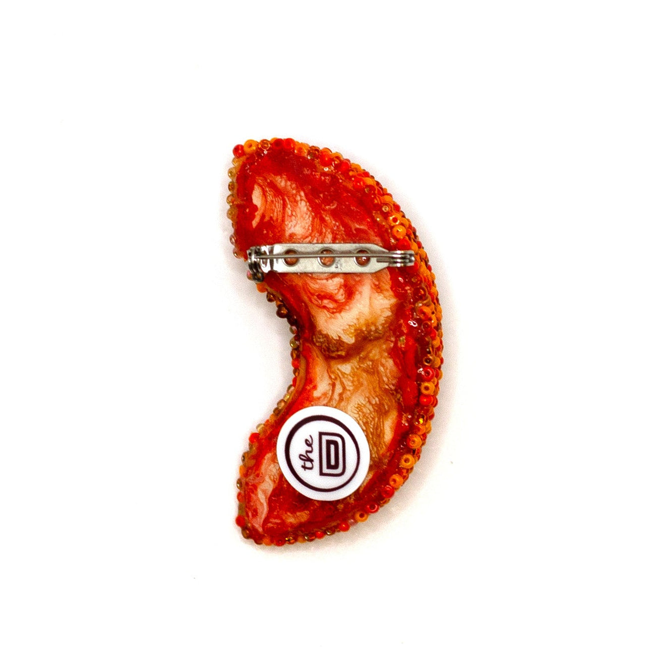 Back view of a handmade beaded orange slice brooch on a white background showing pin fastener.