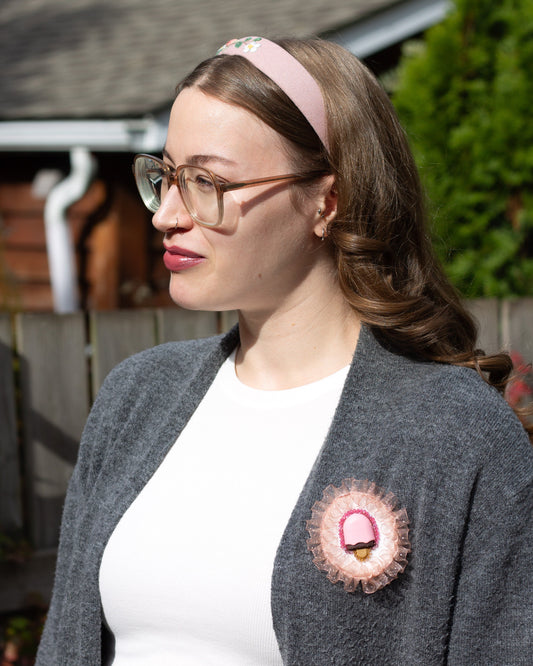 Handmade brooch featuring a popsicle and crystal beads worn on a grey sweater by a young woman.