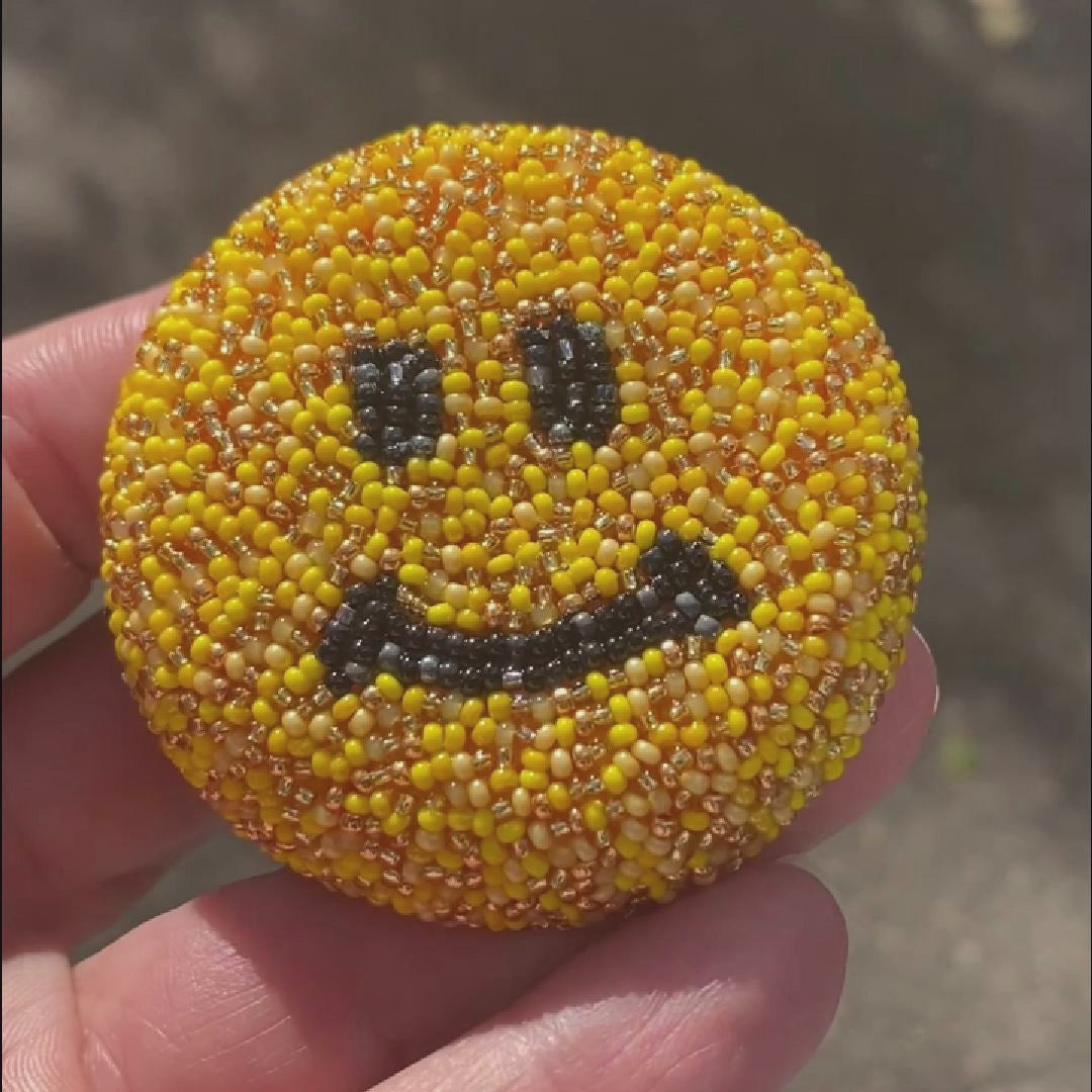 Video of a handmade beaded smiley face brooch taken in the sunlight to show off the sparkle.