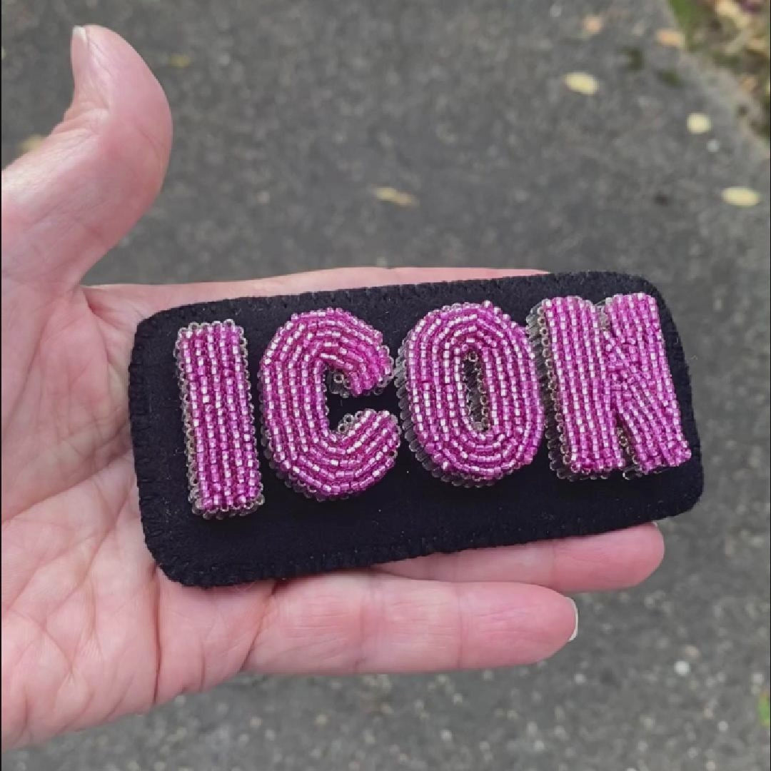 Video of a hand holding a beaded ICON text brooch taken outside to show off the sparkle.