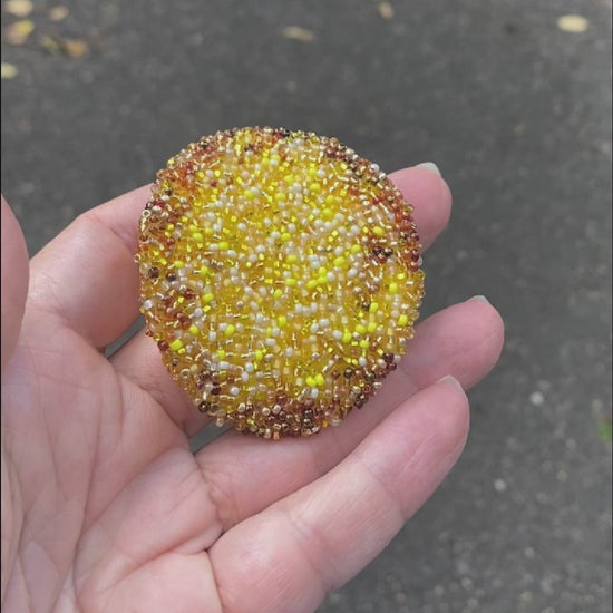 Video of a hand holding a beaded potato chip brooch taken outside to show off the sparkle.