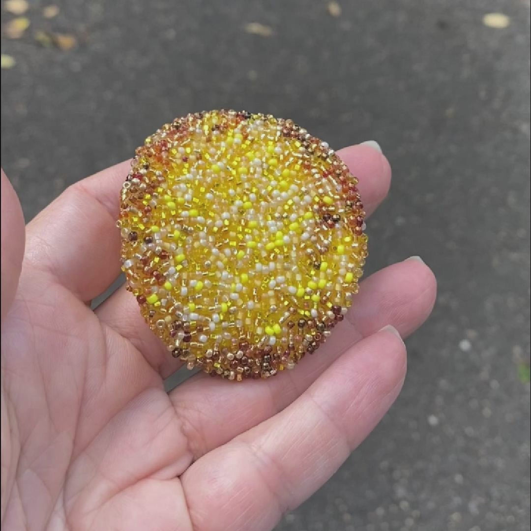 Video of a hand holding a beaded potato chip brooch taken outside to show off the sparkle.