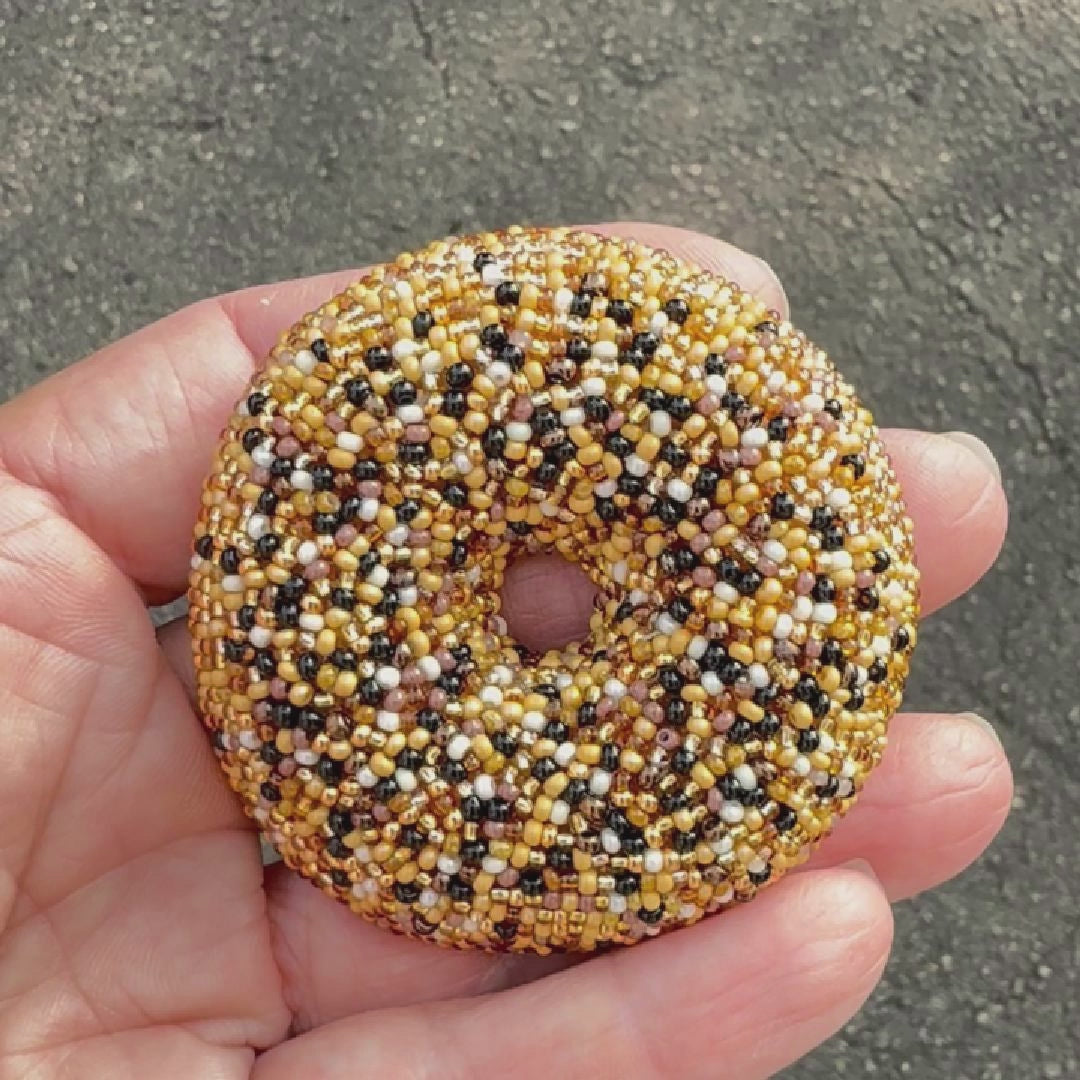 Video of a beaded everything bagel brooch shot outside to show off the bead sparkles.