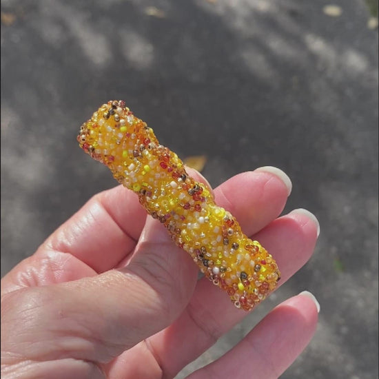 Video of a hand holding a beaded French fry brooch taken outside to show off the sparkle.