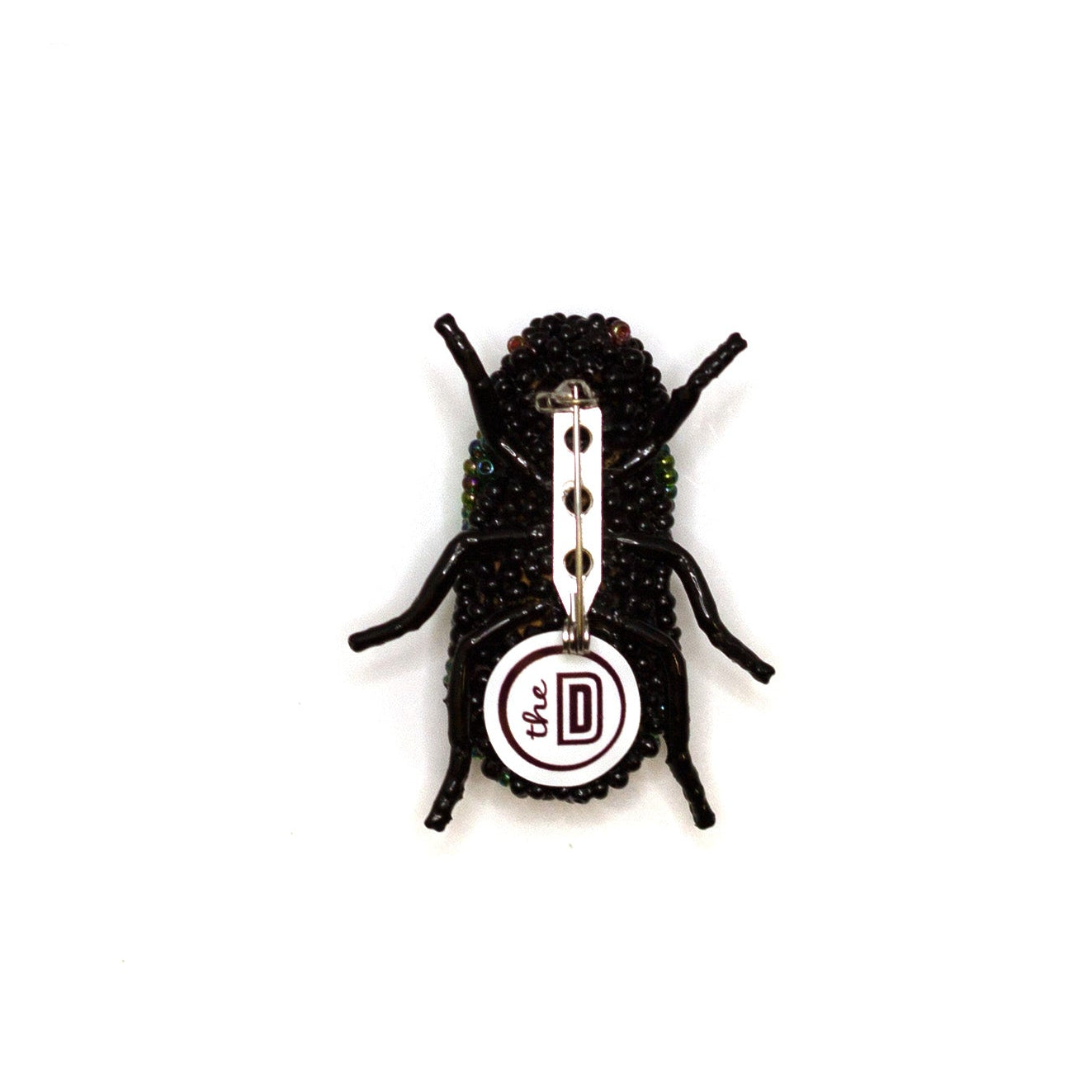 Back view of a green and black handmade beaded beetle brooch on a white background showing pin fastener.