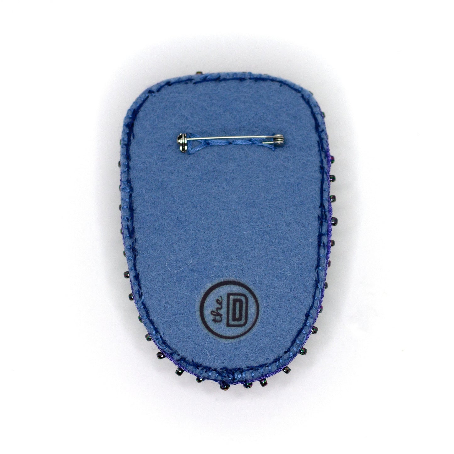 Back view of a handmade sequined brooch featuring a Maleficent doll on a white background showing pin fastener.