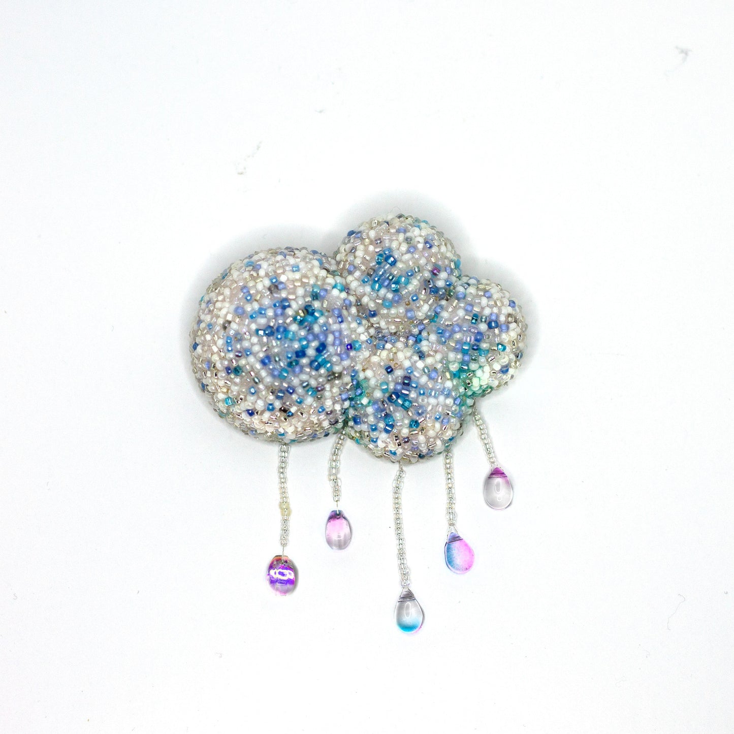 A beaded cloud-shaped brooch with dangling iridescent teardrop charms on a plain white background.