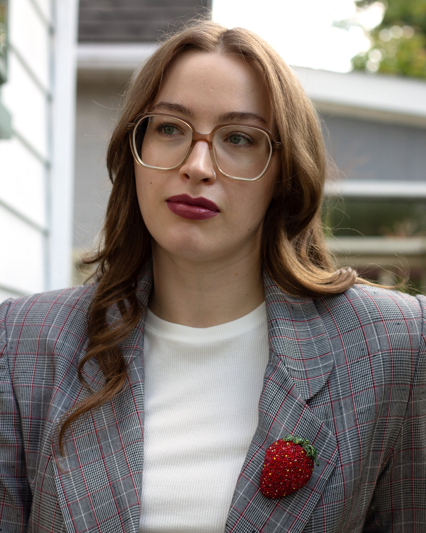 Handmade beaded strawberry brooch worn on a plaid jacket lapel by a young woman.