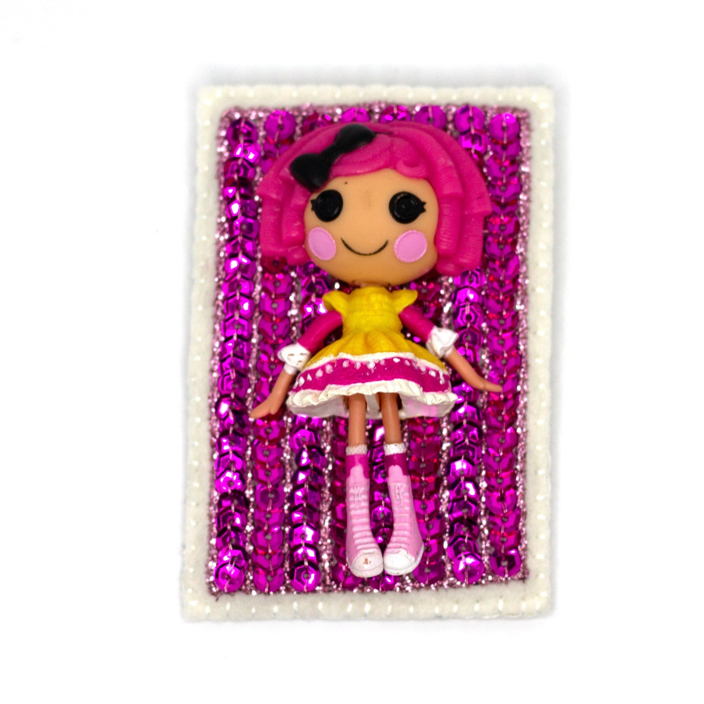 Handmade Lalaloopsy doll brooch covered in pink sequins shown on a white background.