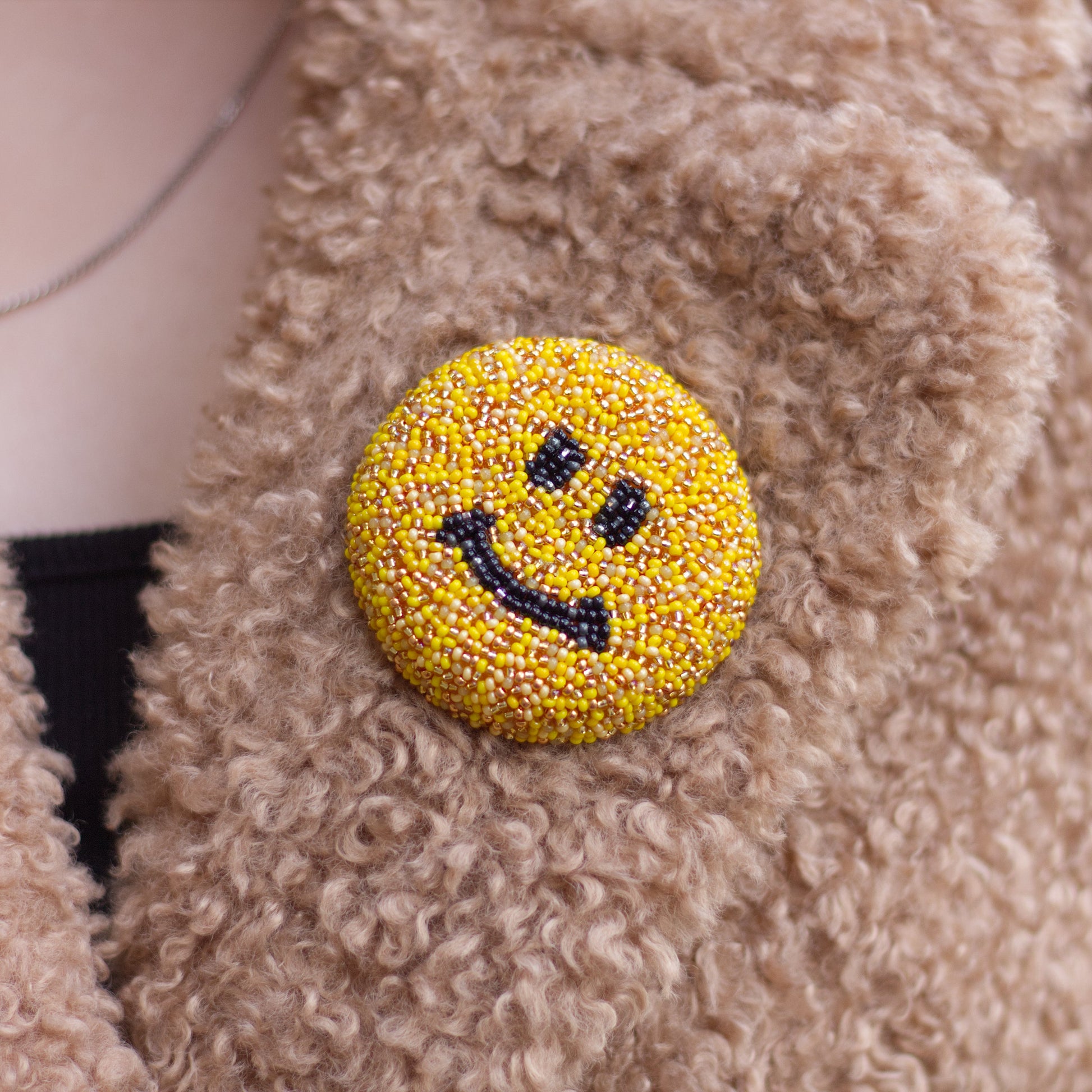 Closeup of a handmade beaded smiley face brooch.
