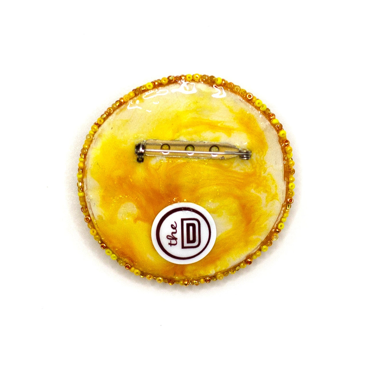 Back view of a beaded smiley face brooch showing the pin fastener and branding.