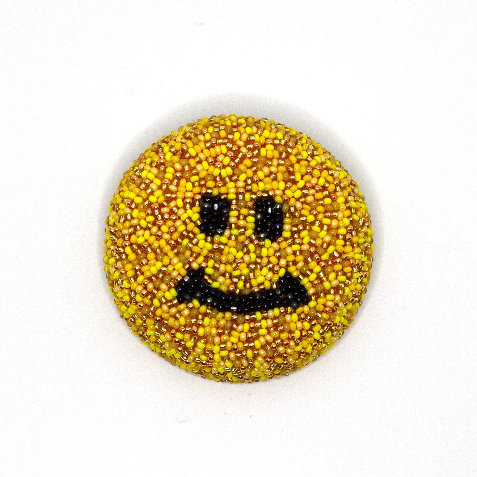 Golden yellow smiley face handmade beaded brooch on a white background.