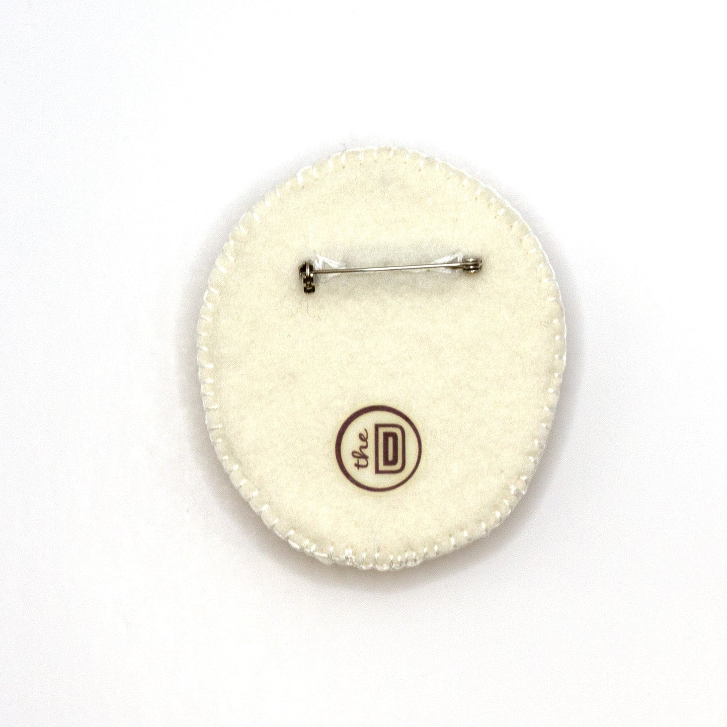 Back view of a handmade embroidered floral brooch featuring Lippy Twozie on a white background showing pin fastener.
