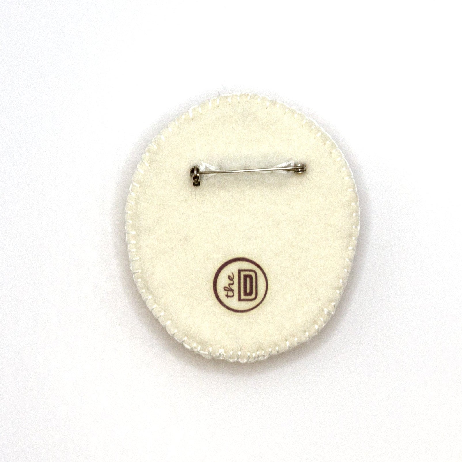 Back view of a handmade embroidered floral brooch featuring Lippy Twozie on a white background showing pin fastener.