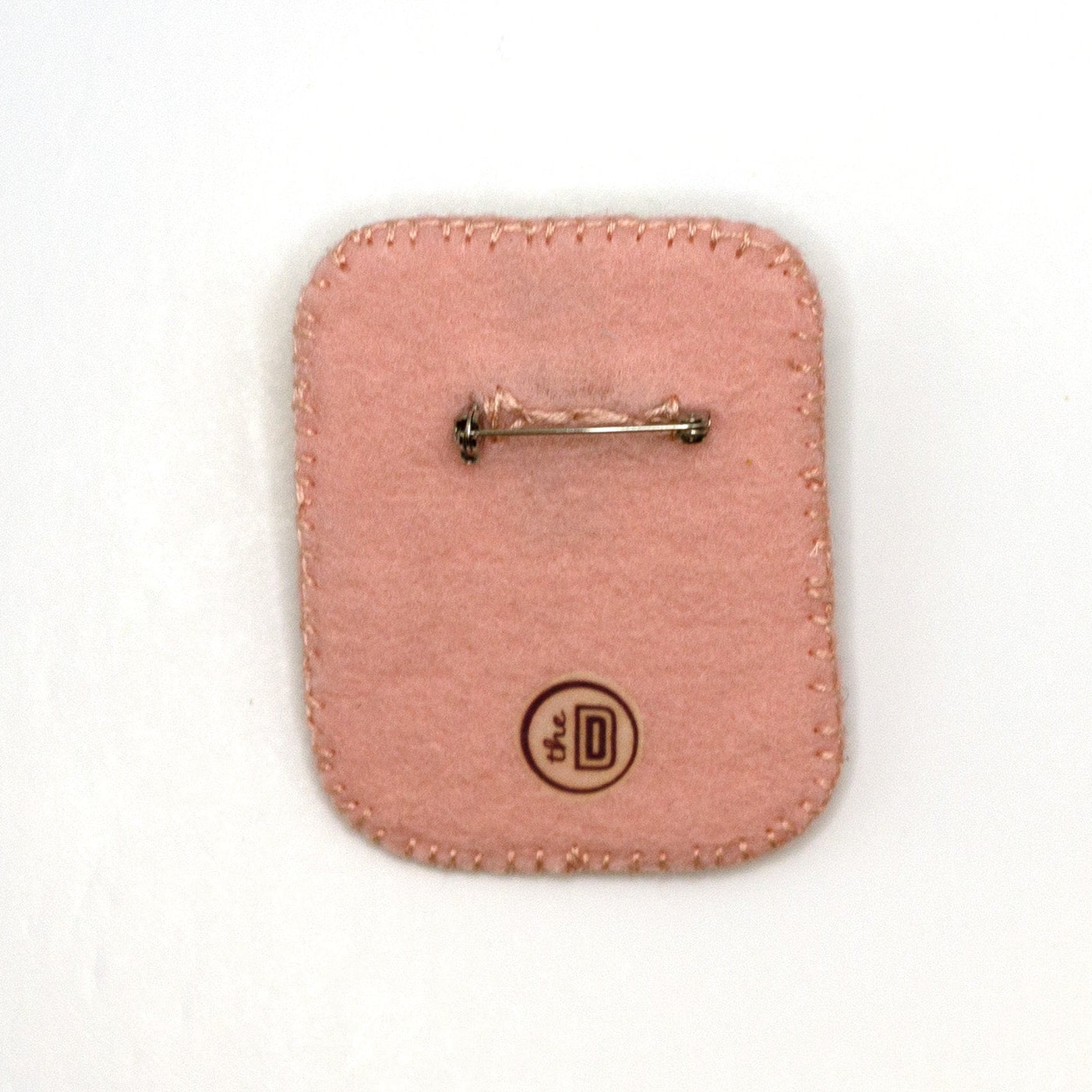 Back view of a handmade embroidered beach scene brooch featuring a starfish on a white background showing pin fastener.